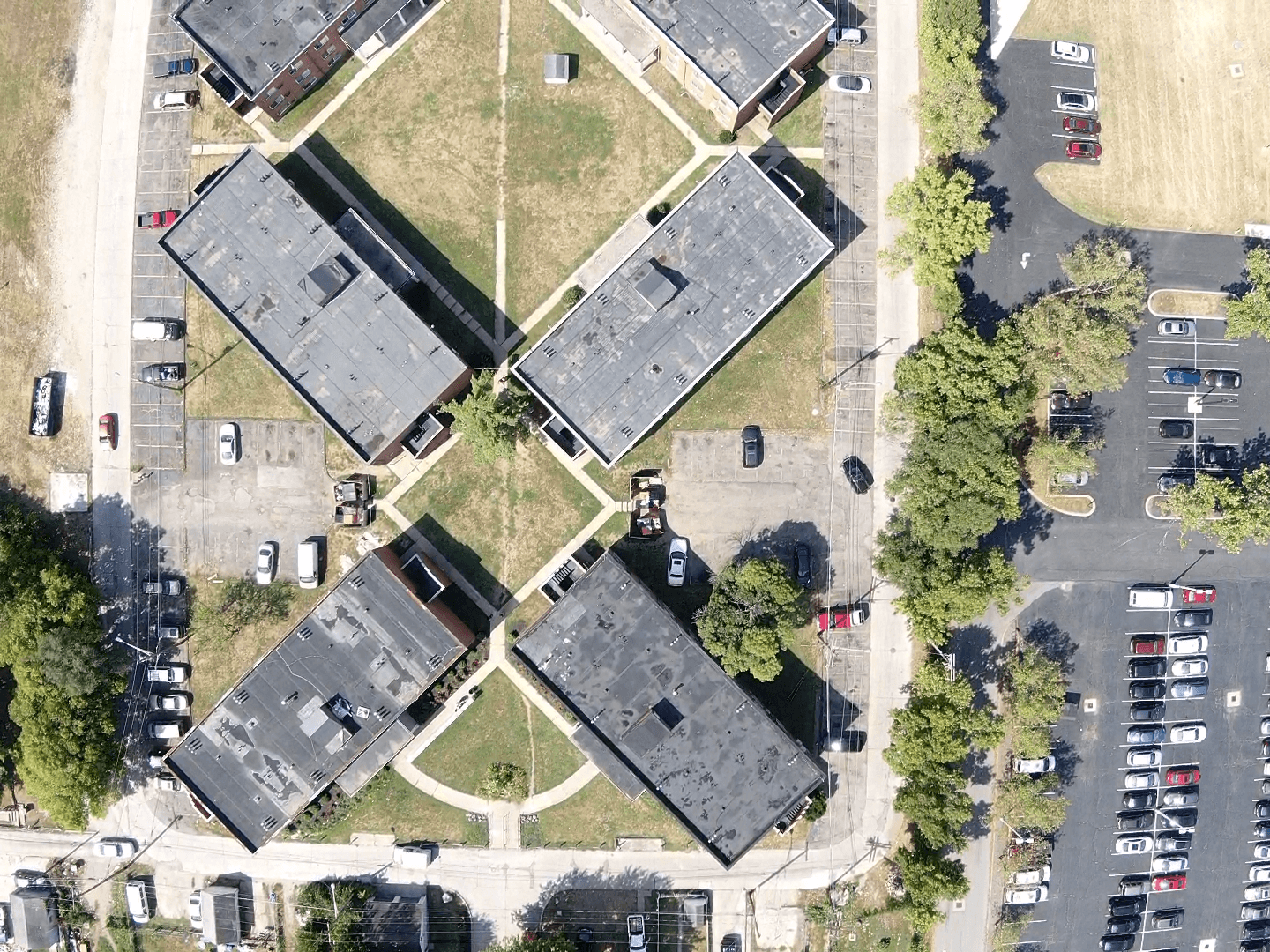 An aerial view of flat-roof buildings surrounded by lawns, walkways, and parking areas