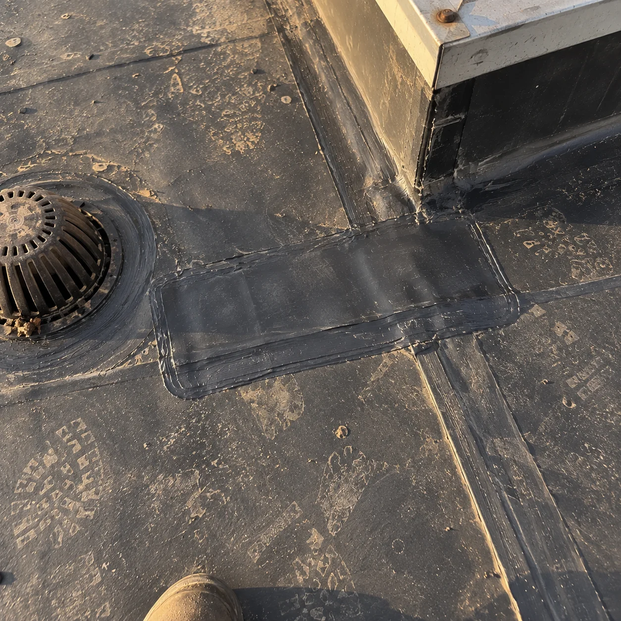 Roof repairs around a drain and equipment curb.
