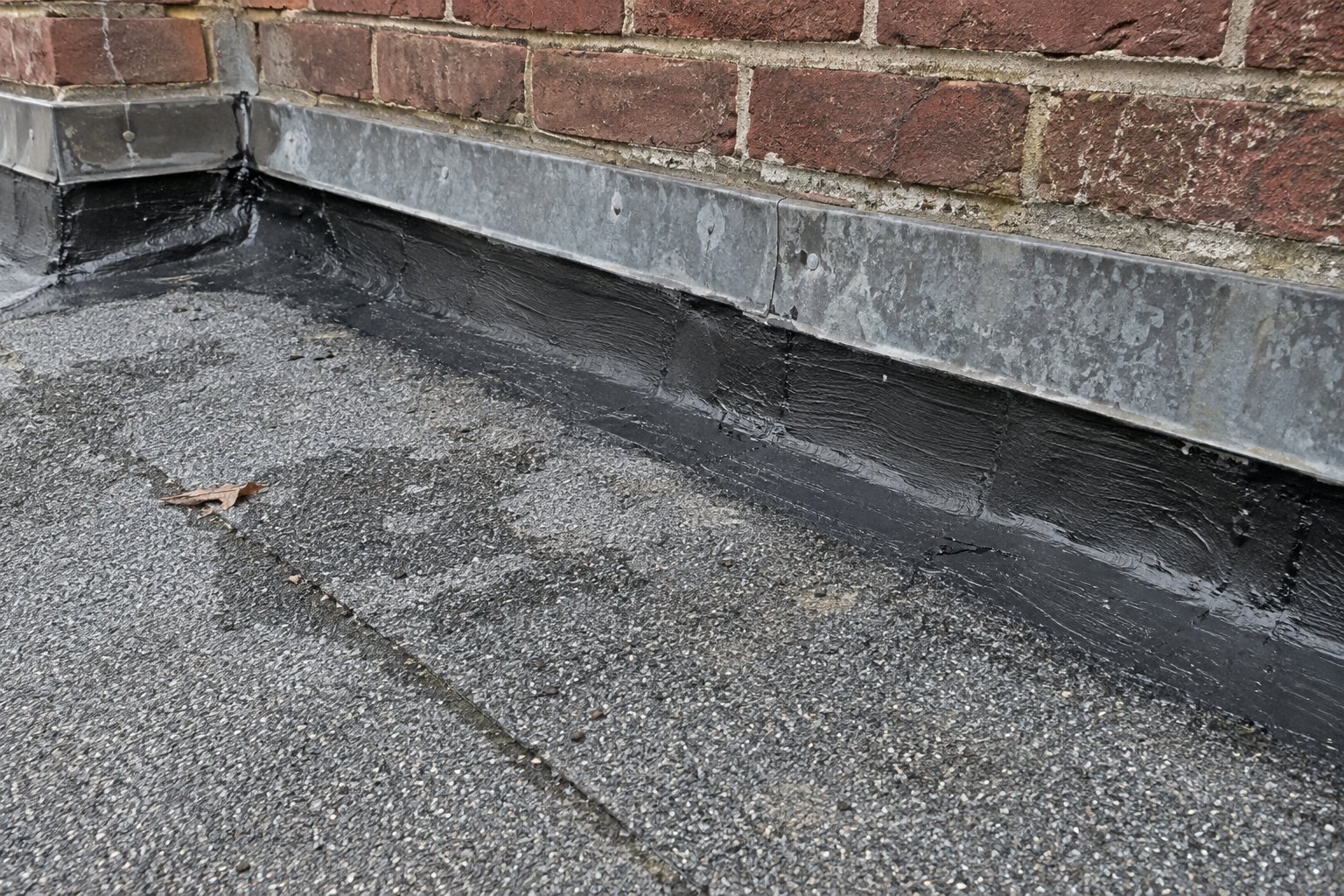 Illustration of repaired base flashing along an old brick parapet