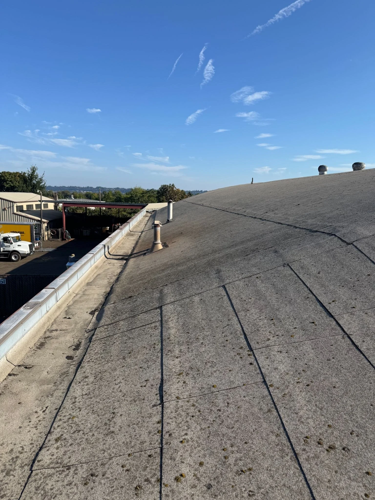 Domed commercial torch-down roof with overlapping sheets, vent pipes, and a metal perimeter edge