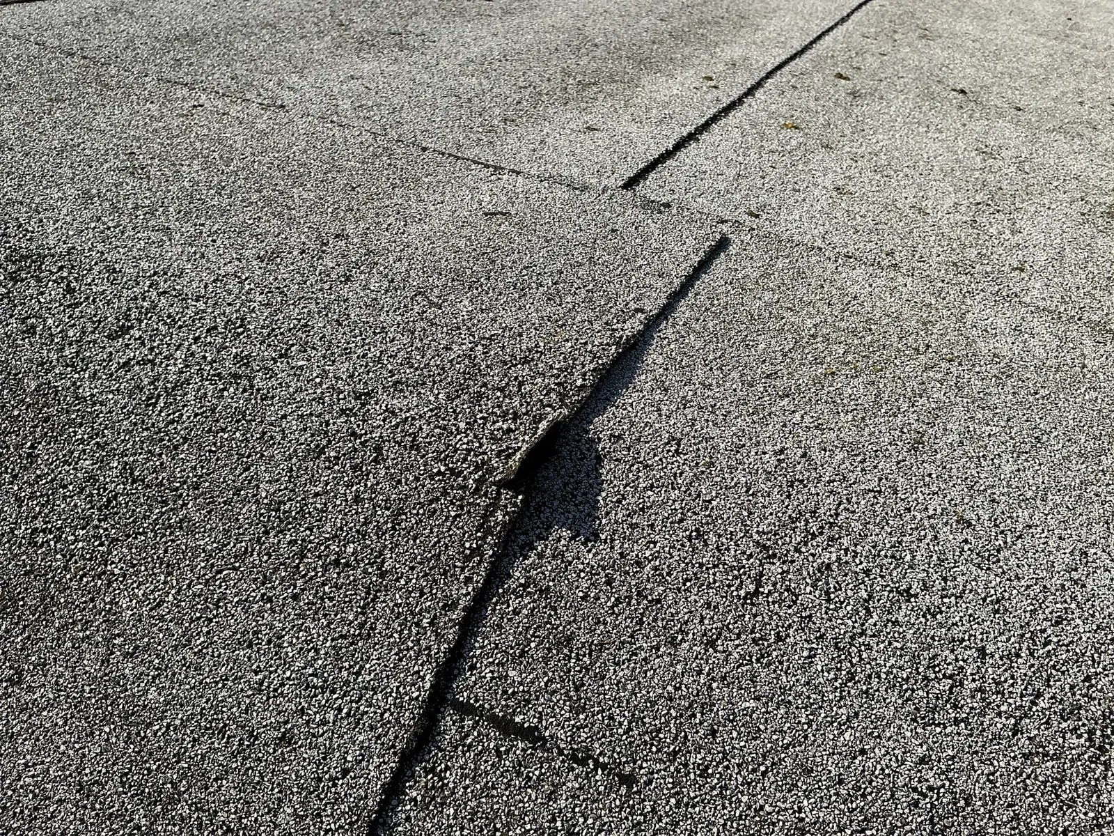 A lifted edge where two sheets of granule-covered roofing overlap