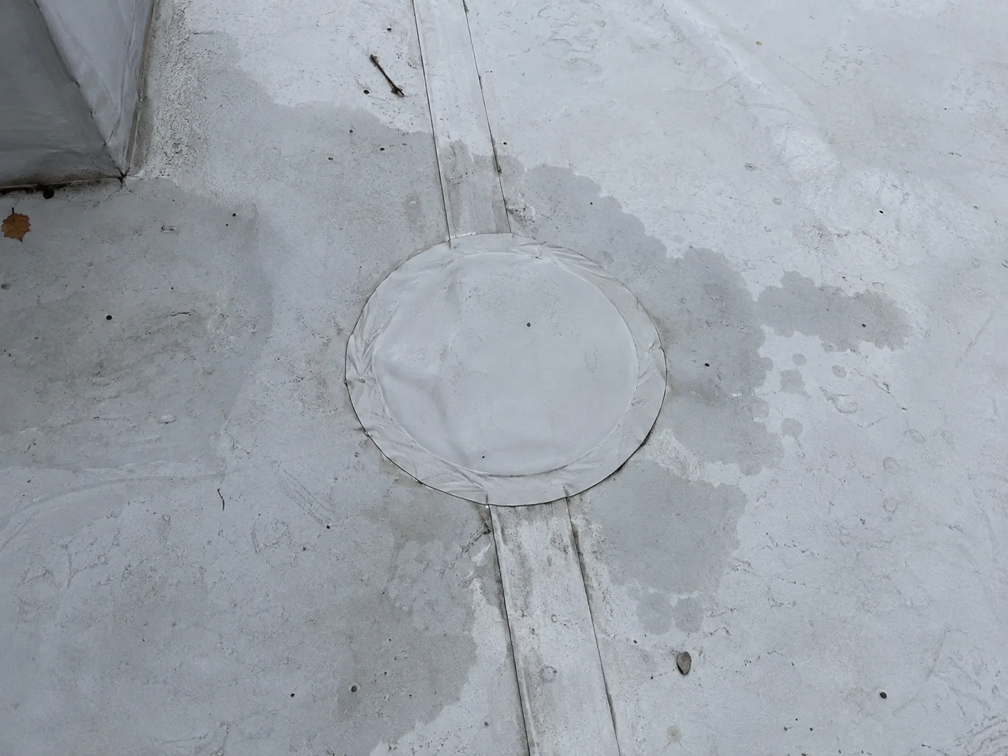Circular repair patch on a white roof membrane.