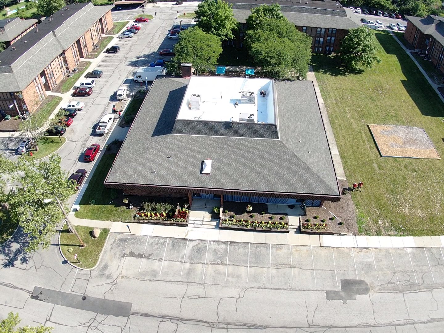A crew’s truck staged in the parking lot while a new roof goes on above an occupied office building