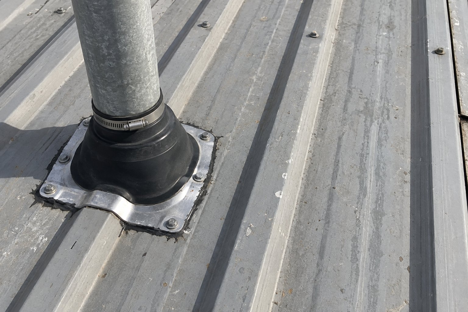 Illustration of a sealed pipe boot on an aged ribbed metal roof
