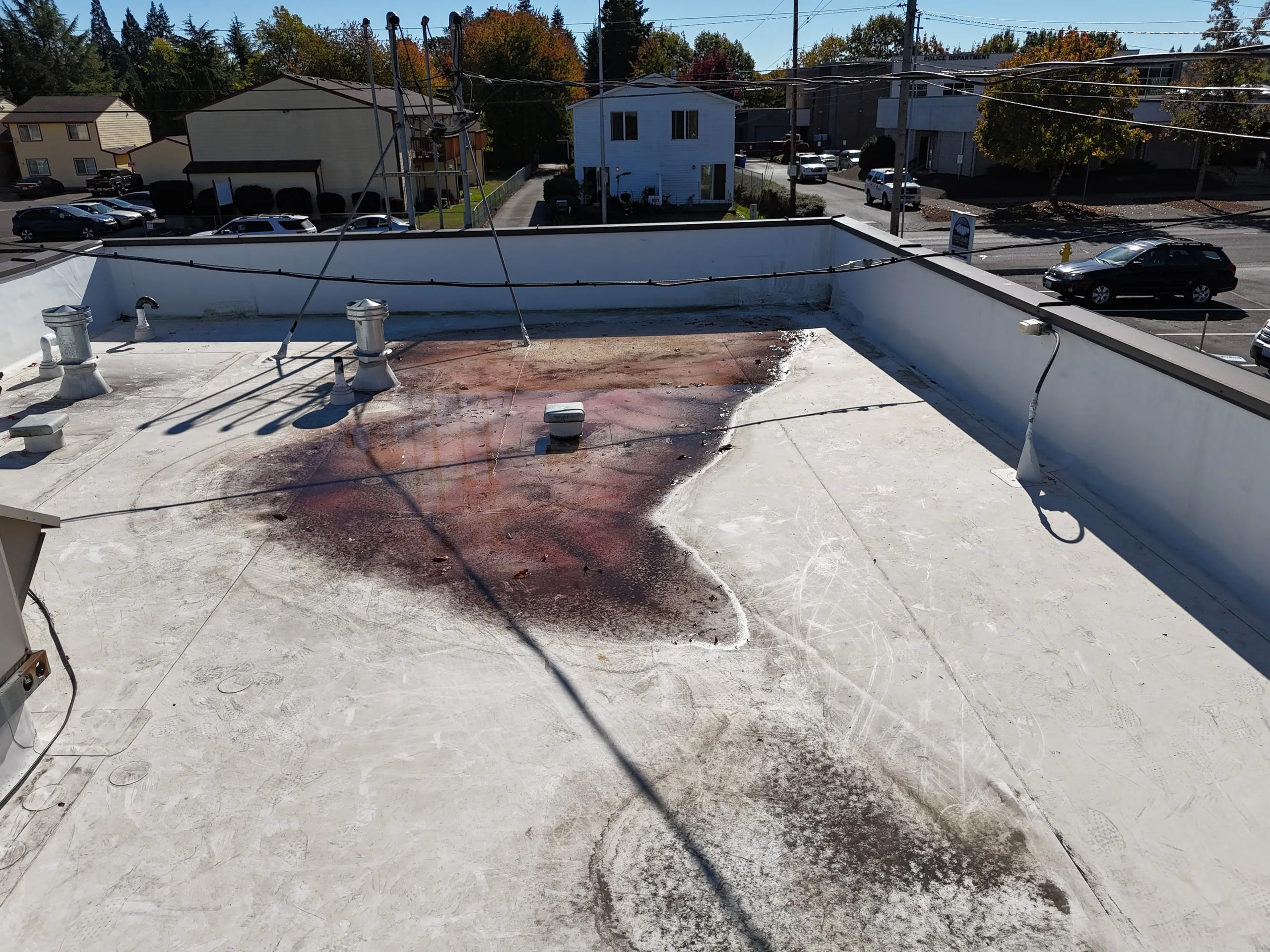 A large rust-colored stain where water has sat in the middle of a white flat roof.