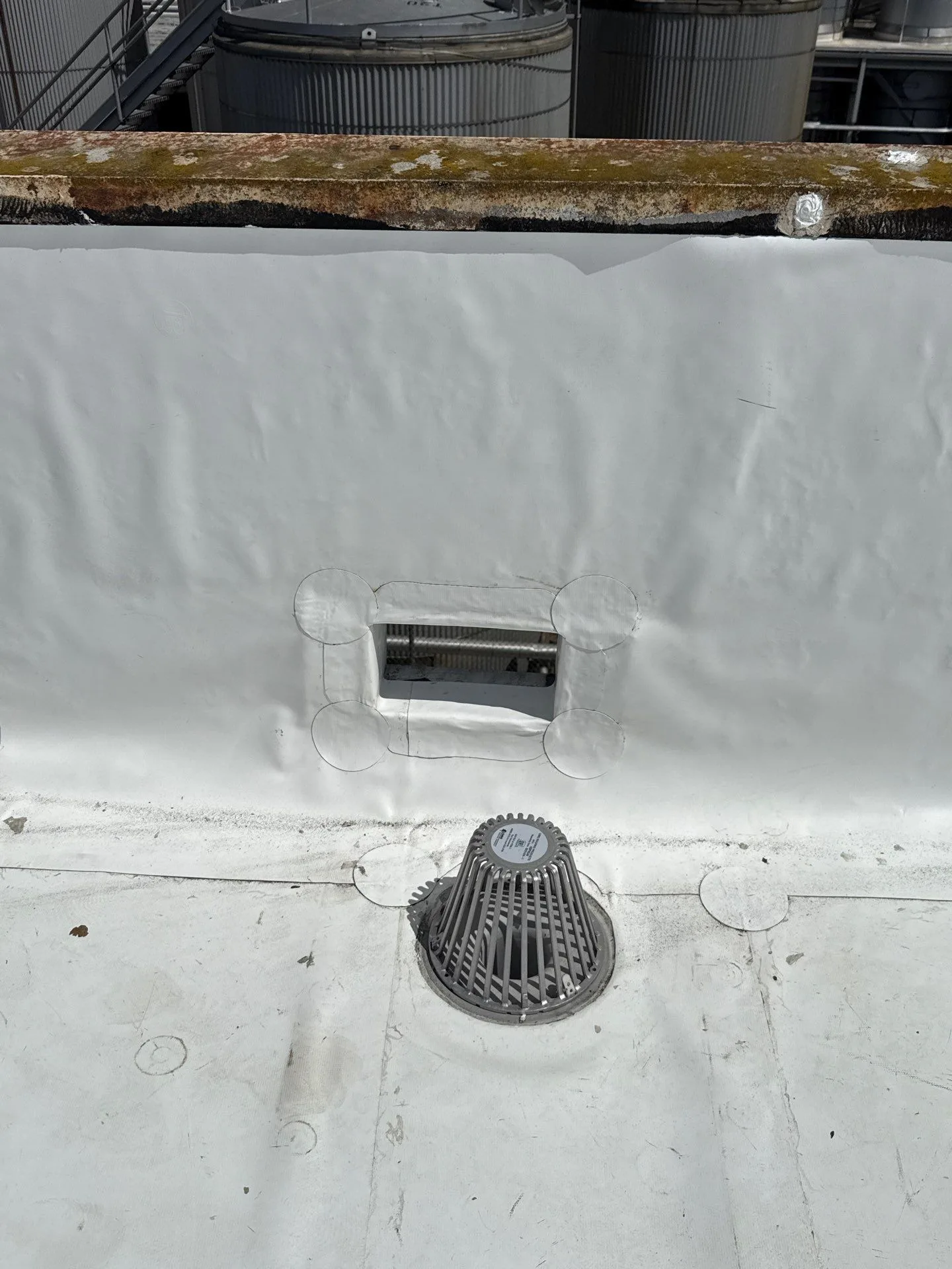 A new roof drain set into a freshly rebuilt section of white flat roof.