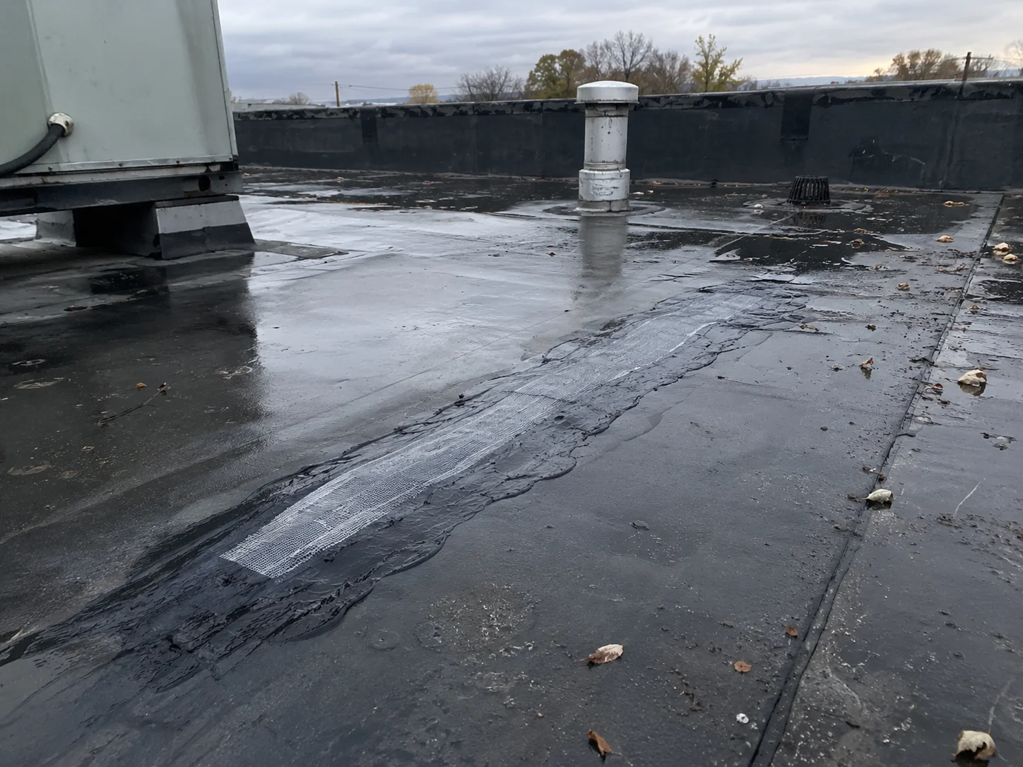Reinforced seam repair across a dark flat roof.