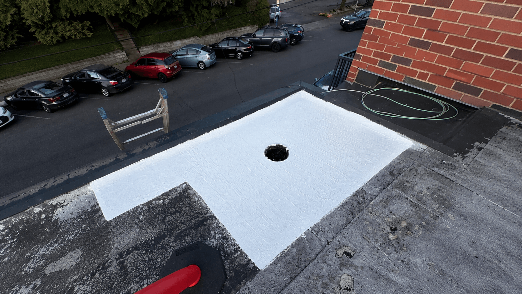 A completed white membrane repair around a commercial roof drain