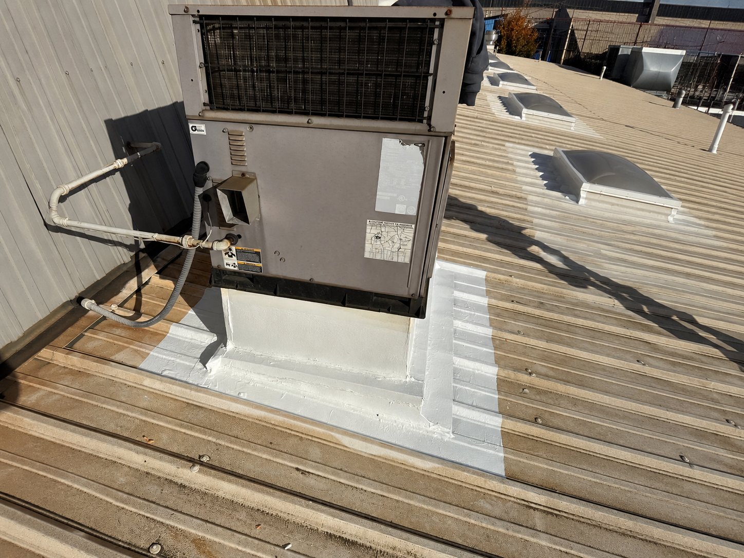 A newly coated repair around a rooftop equipment curb