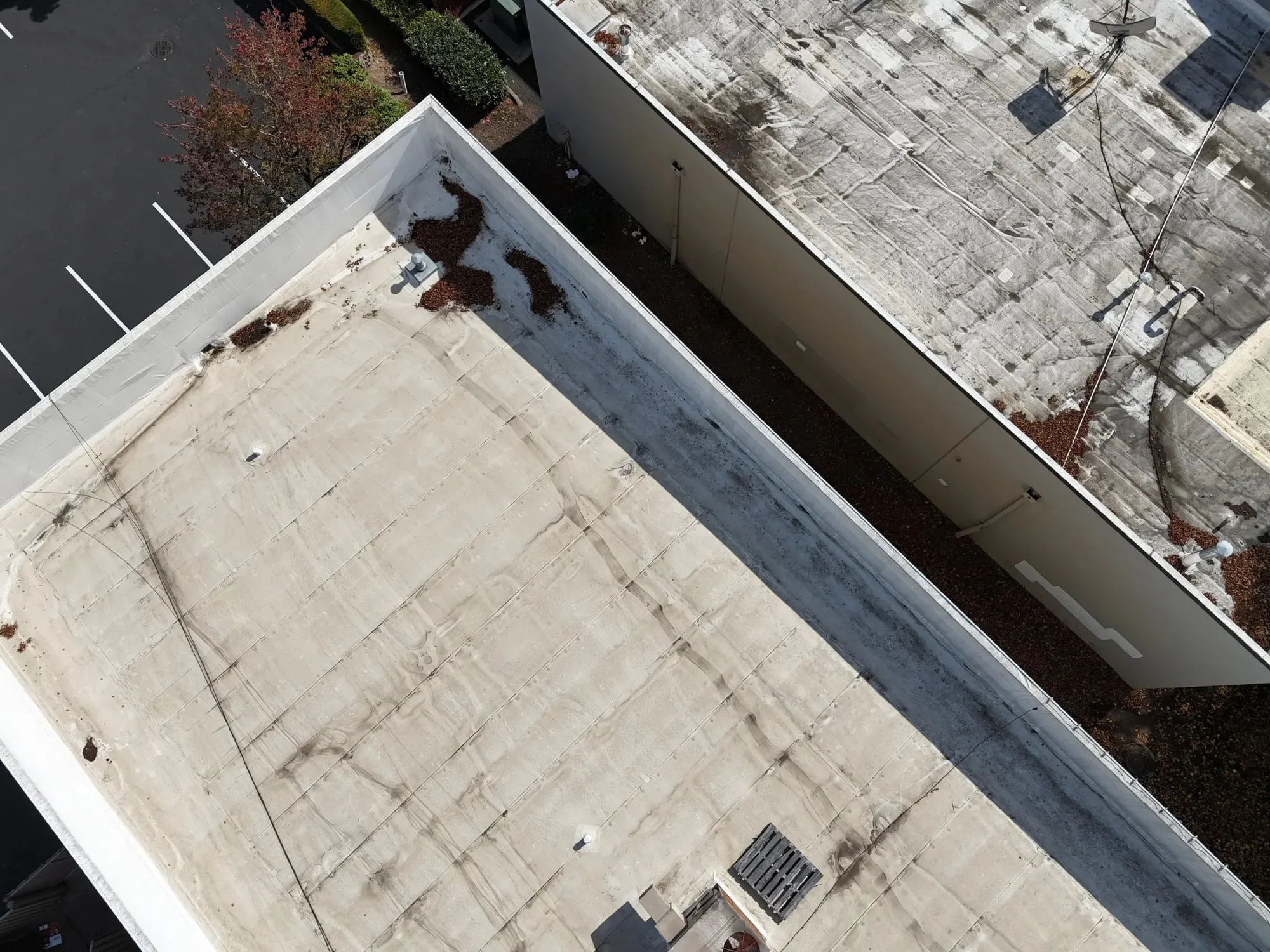 A large flat roof seen from above, with long seams running across it between the parapet walls.