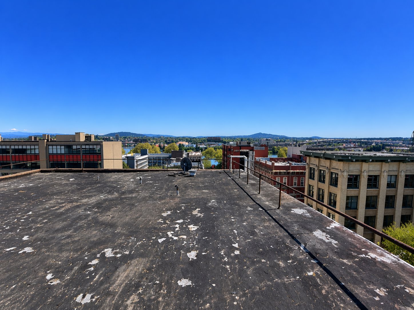 An aged commercial roof with patch scars spread across the entire field