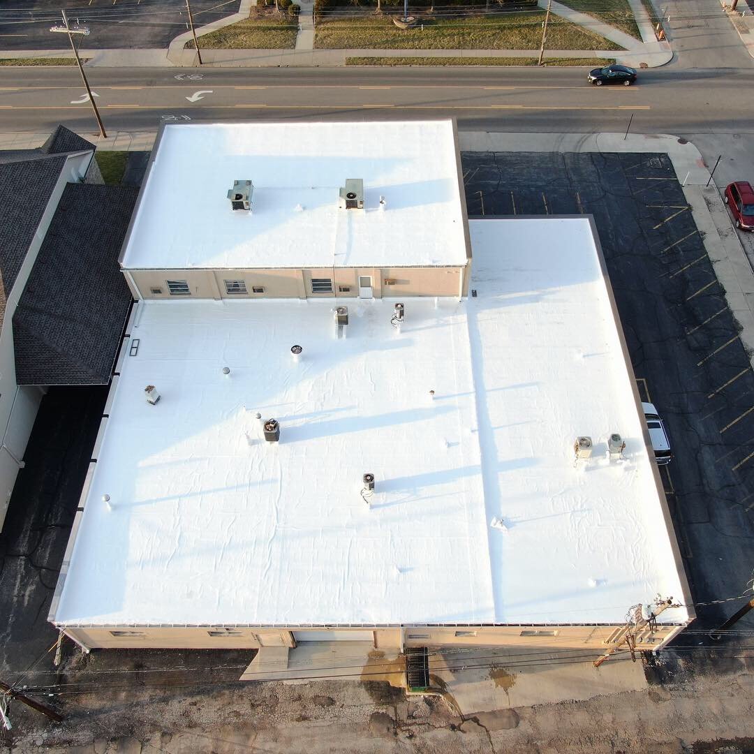 A commercial building whose entire flat roof has been resealed in bright white silicone, seen from above