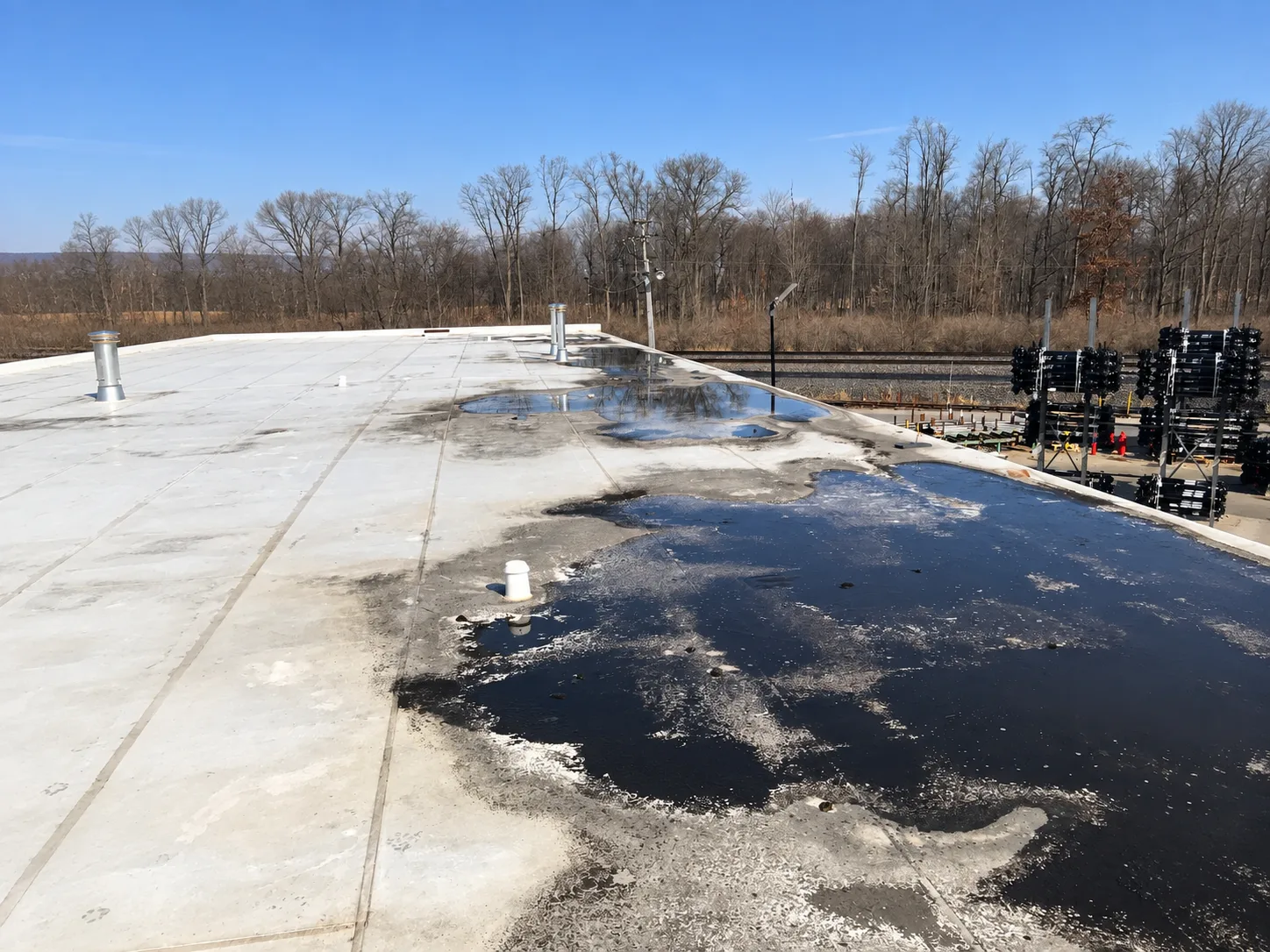 Several pools of standing water along the edge of a white low-slope roof
